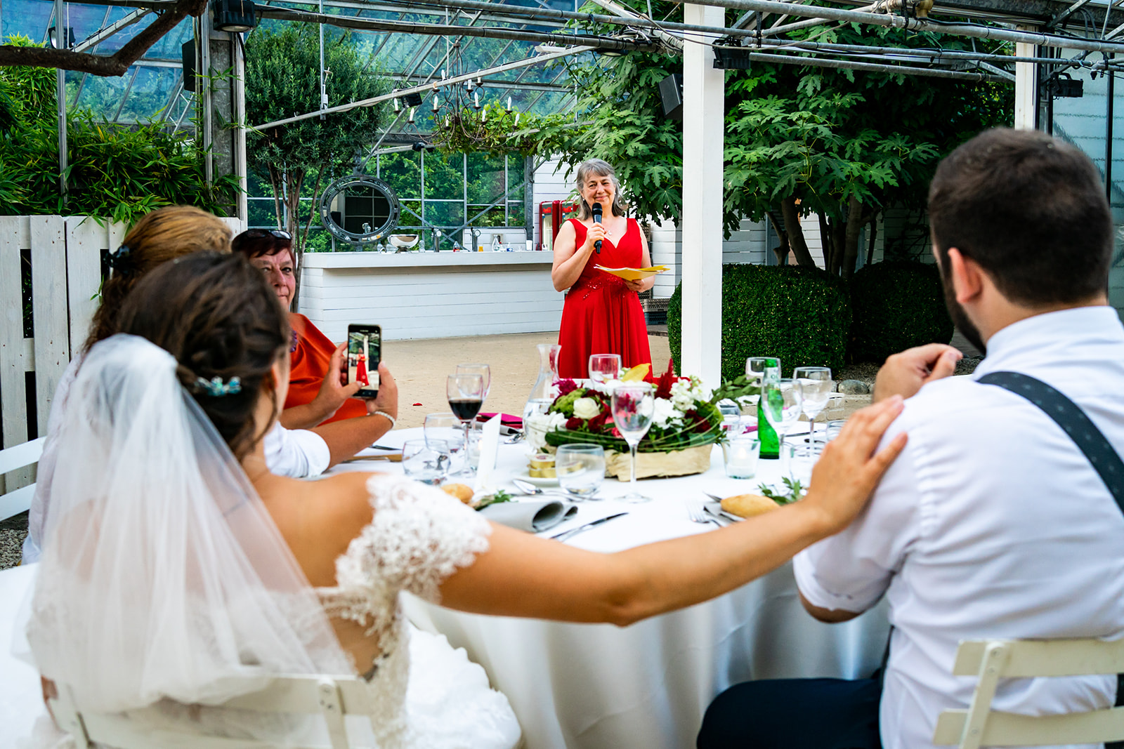 La mariée pose sa main sur l'épaule du mariée durant le discours de la maman sous la serre du domaine de Béronsart