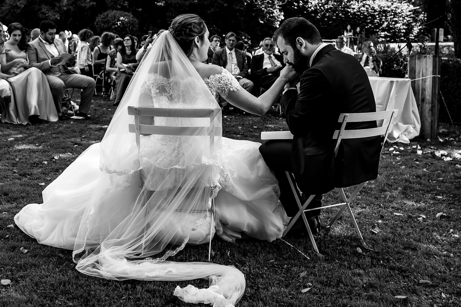 Le marié embrasse la main de la mariée durant la cérémonie religieuse dans les jardins du domaine de Béronsart à Gesves.
