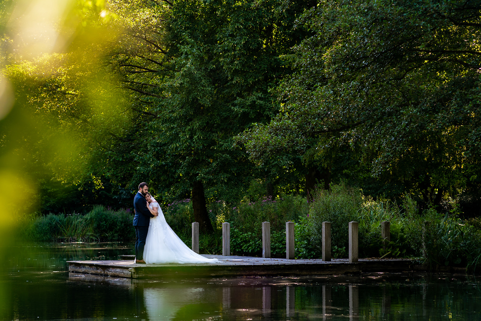 Les mariés posent sur le ponton de l'étang du domaine de Béronsart à Gesves durant le golden hour.