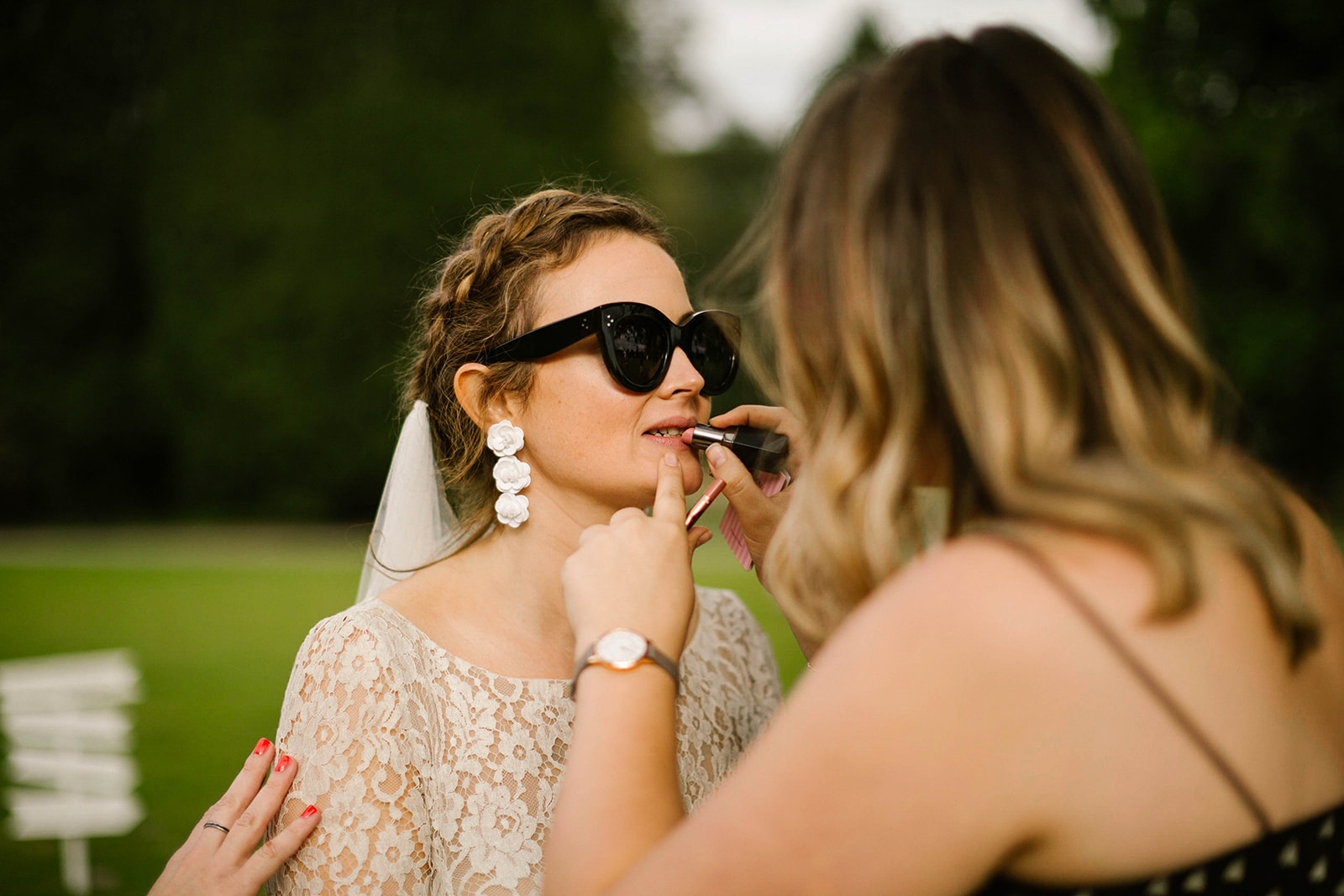 bride applies lipstick at wedding