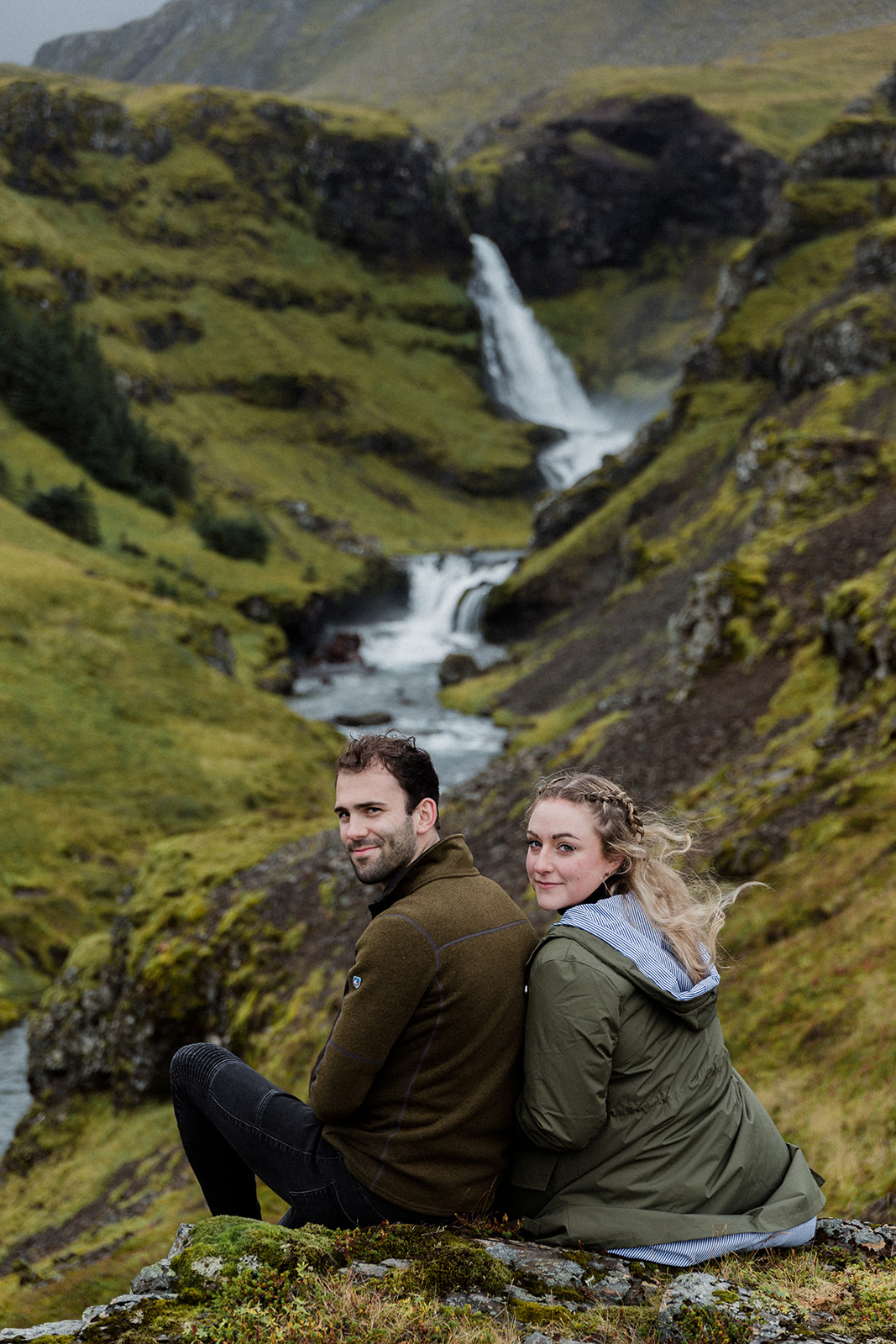 A couple sitting in front of a stunning waterfall enjoying an adventure session photography in Iceland