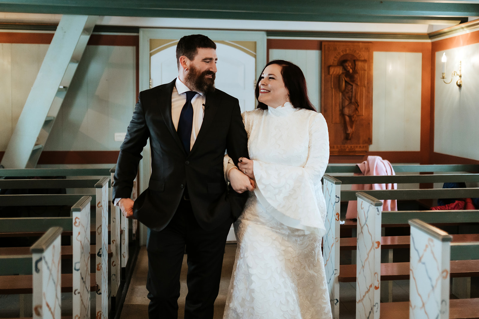 Couple is walking down the isle in the black church in Iceland