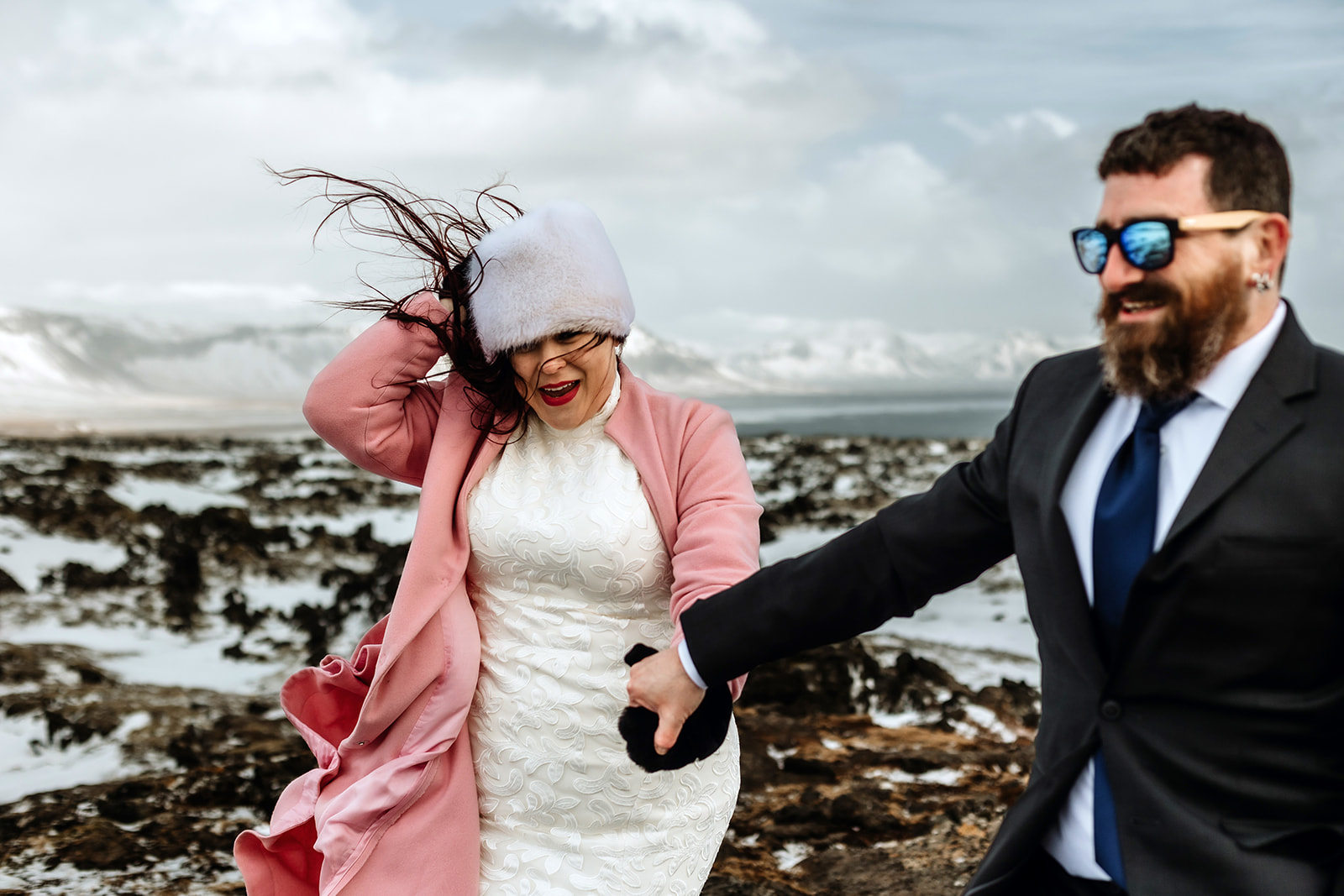 Married couple who got married in Iceland are standing on top of a mountain and surrounded by snow and mountains