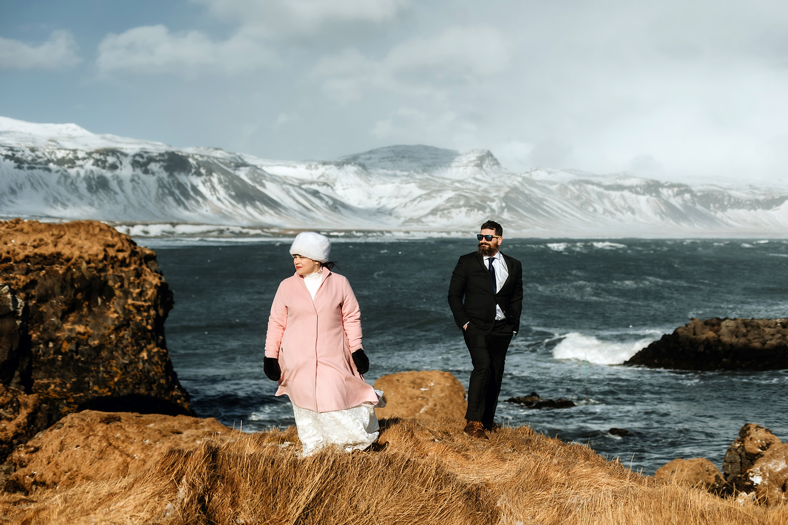 Married couple is hugging in front of a stormy Ocean in Iceland on their wedding day