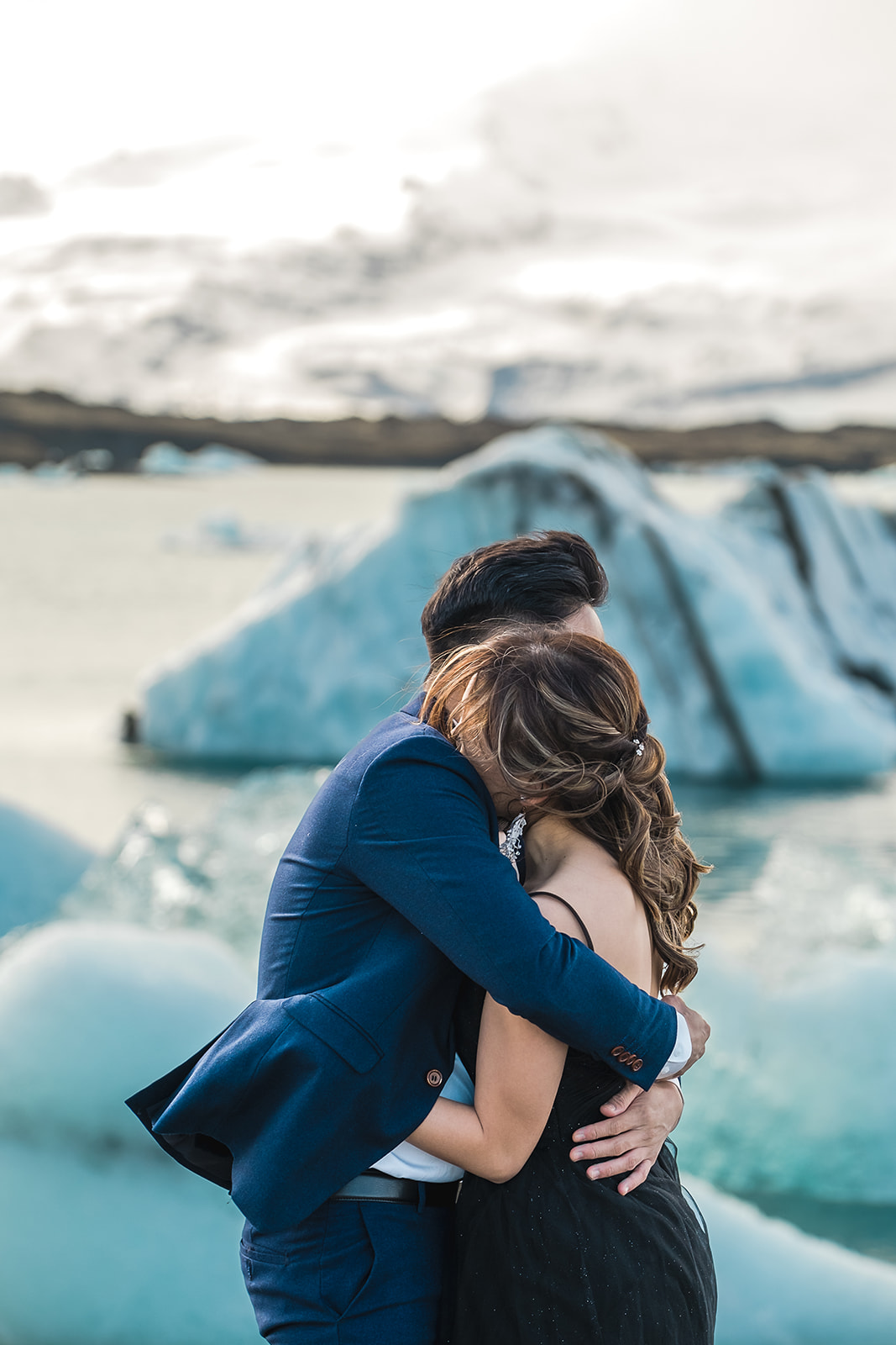A couple hugging in front of Icebergs Pre-wedding Adventure Session at Jökulsárlón Glacier Lagoon Iceland black dress