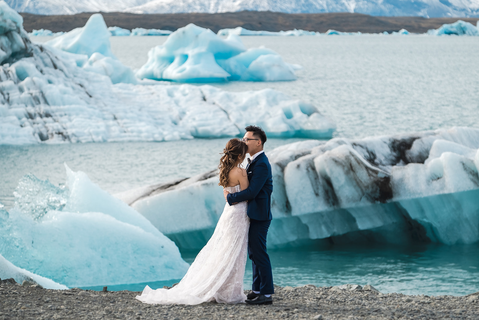A couple standing in front of Icebergs Pre-wedding Adventure Session at Jökulsárlón Glacier Lagoon in Iceland