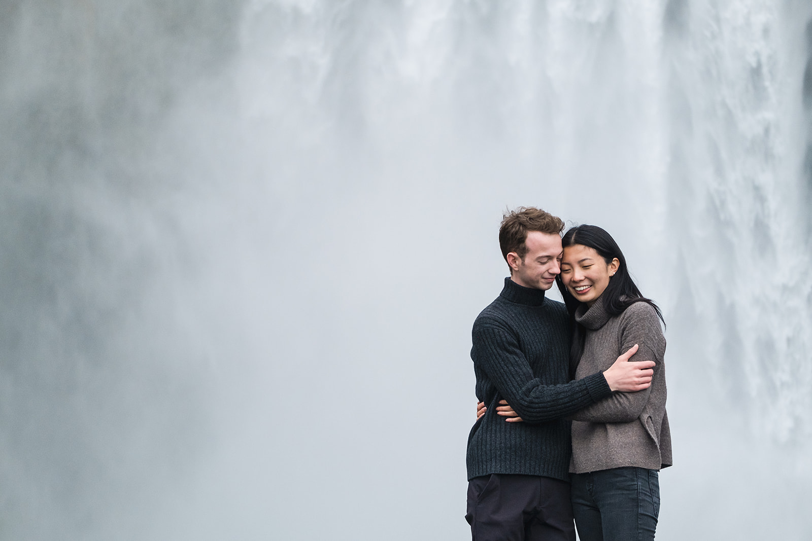 Couple standing in front of Skogafoss waterfall in Iceland