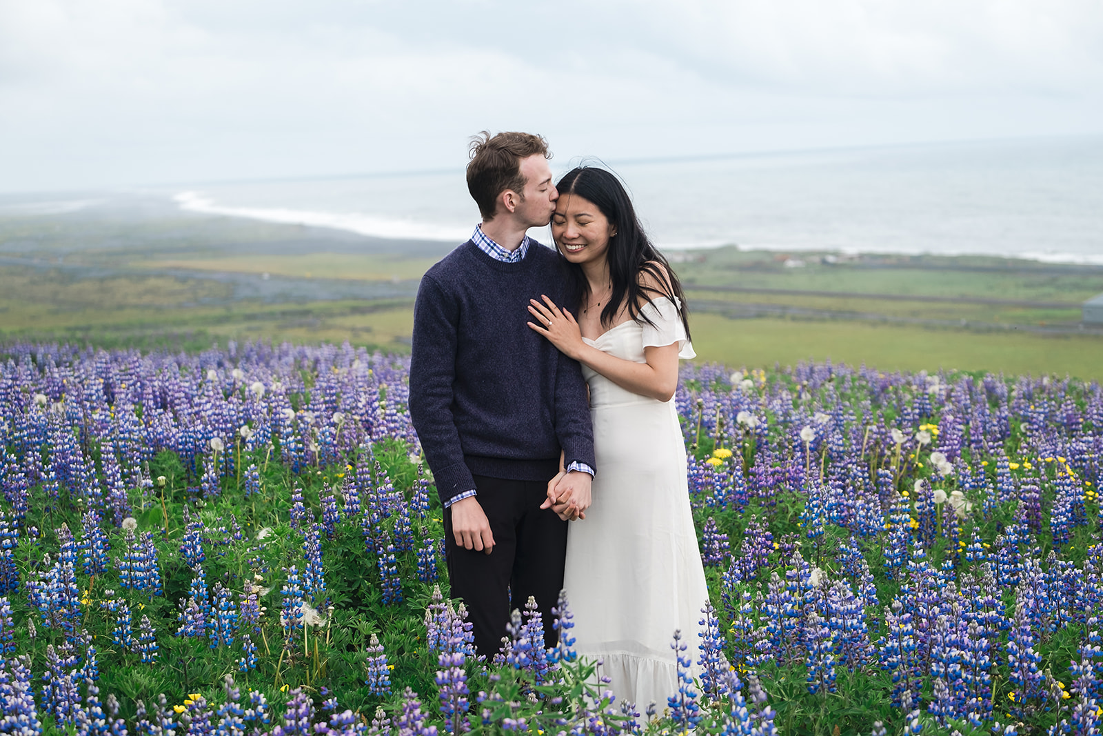 Couple standing in a lupines field in Iceland during the summer