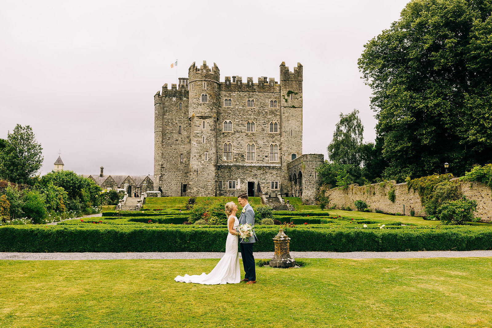 Newly married couple kiss with kilkea castle in background