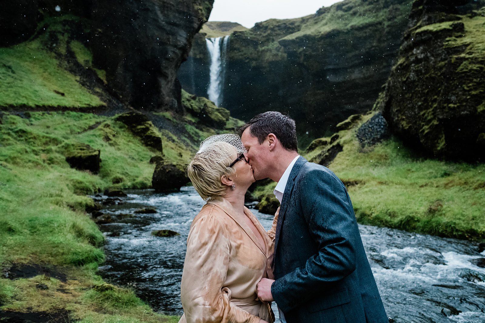 A couple kissing under the rain in front of Kvernufoss Waterfall in Iceland
