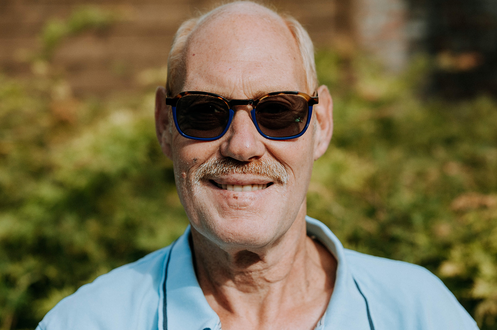 Portretfoto man zonnebril buiten zon mooi weer knap lach gelukkig