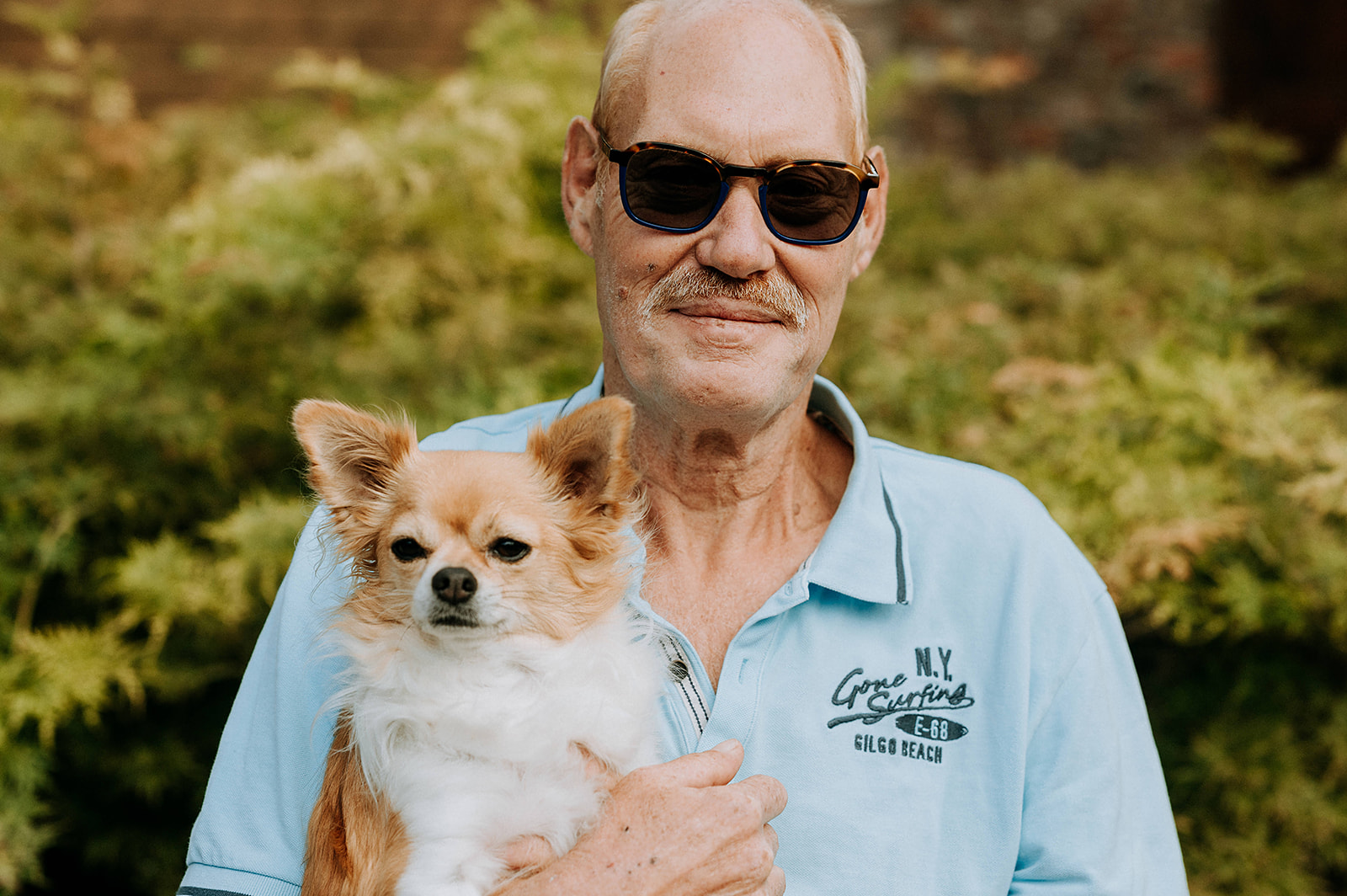 Portretfoto van man met hond buiten portret mooi weer zon zonnebril