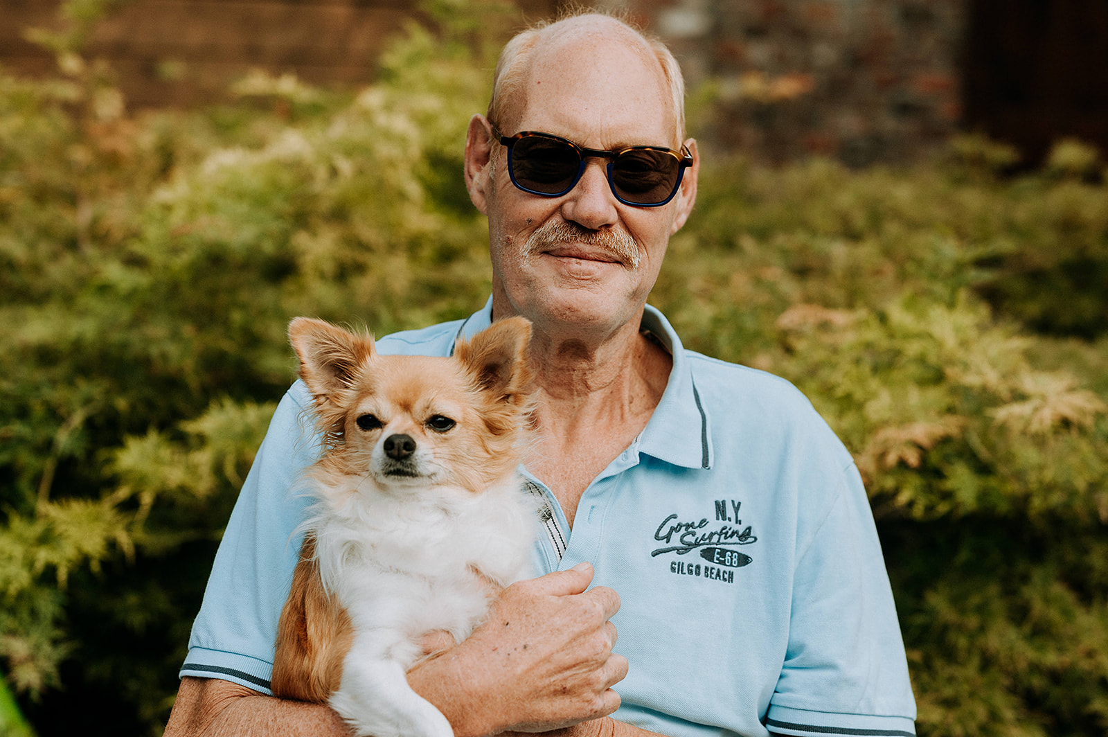 Portretfoto van man met hond buiten portret mooi weer zon zonnebril