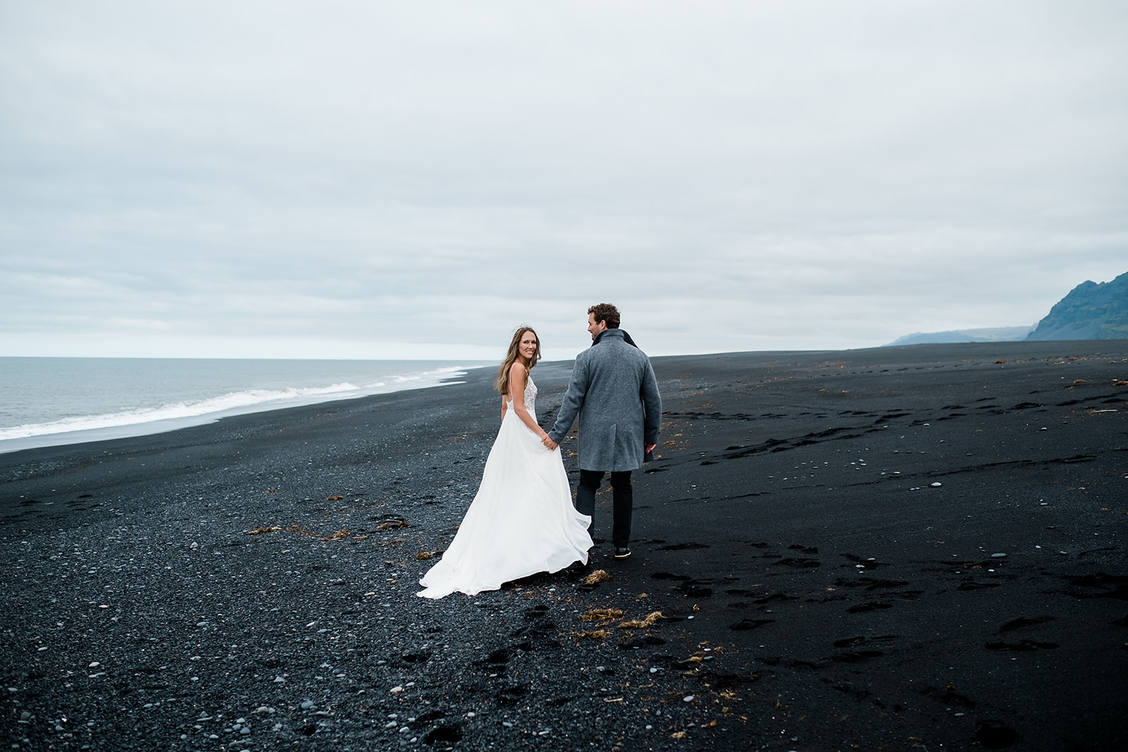 just married couple walking on a black sand beach in Iceland