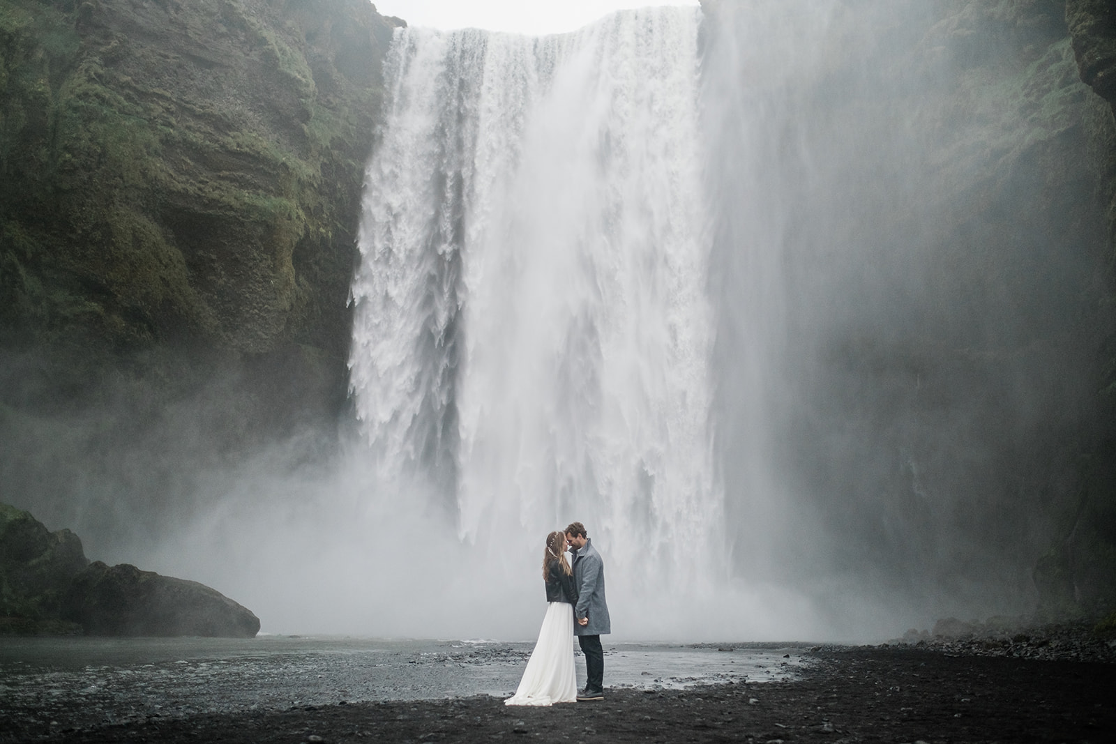 couple kissing in front of Skogafoss waterfall in Iceland