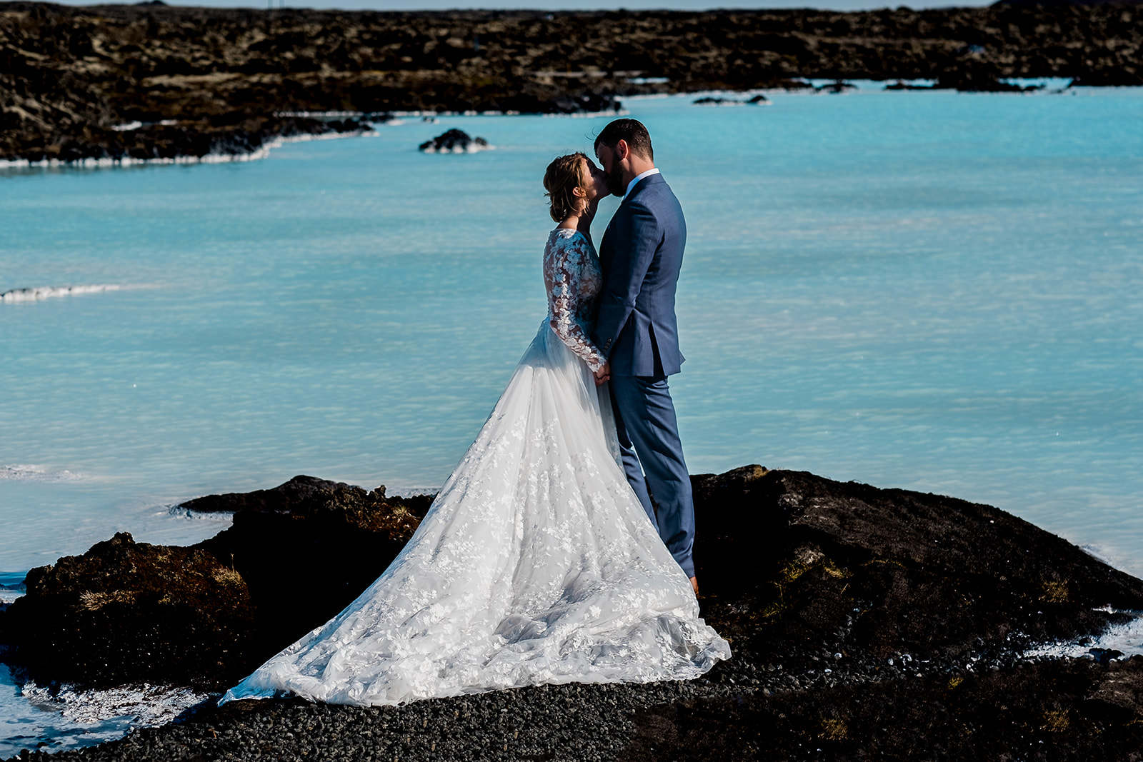 A stunning couple standing and hugging at the Blue Lagoon during their Ethereal Summer Elopement at Reykjanes Peninsula
