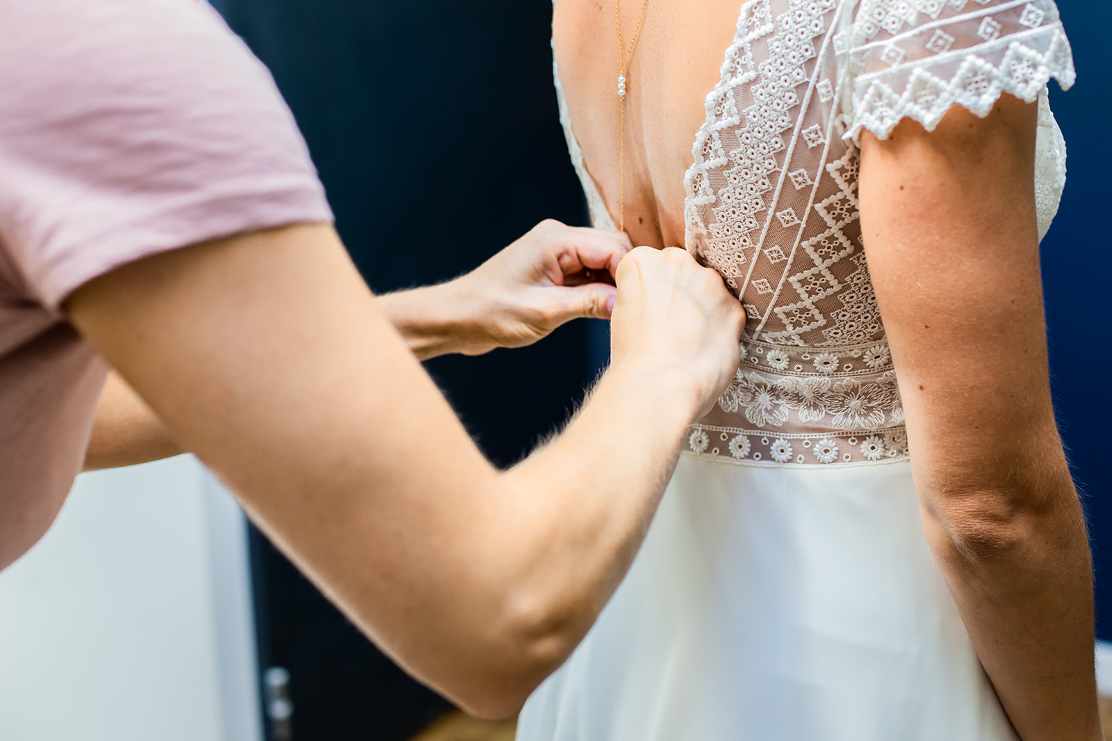 La sœur de la mariée l'aide à boutonner sa robe