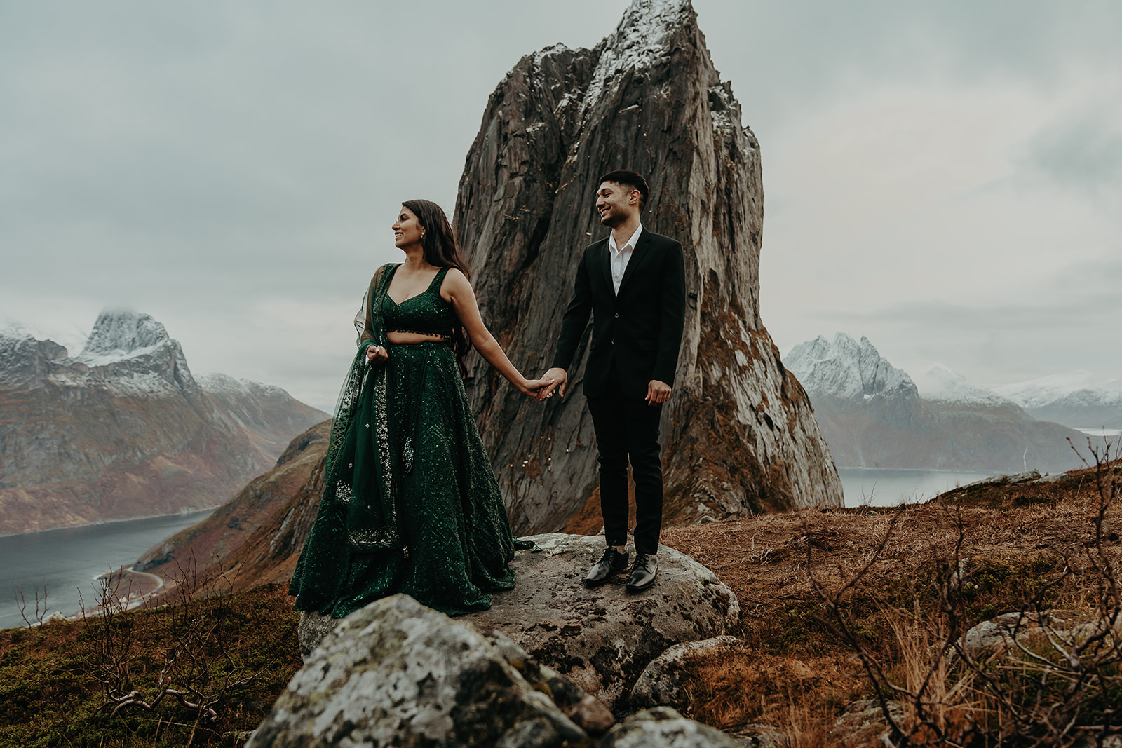 Couple dressed in traditional Indian clothes holding hands on top of a mountain in senja, Norway