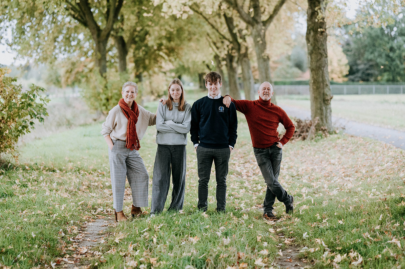 Familiefoto in het groen, genomen in een bospad. Op de foto zie je een gezin met 2 kinderen.