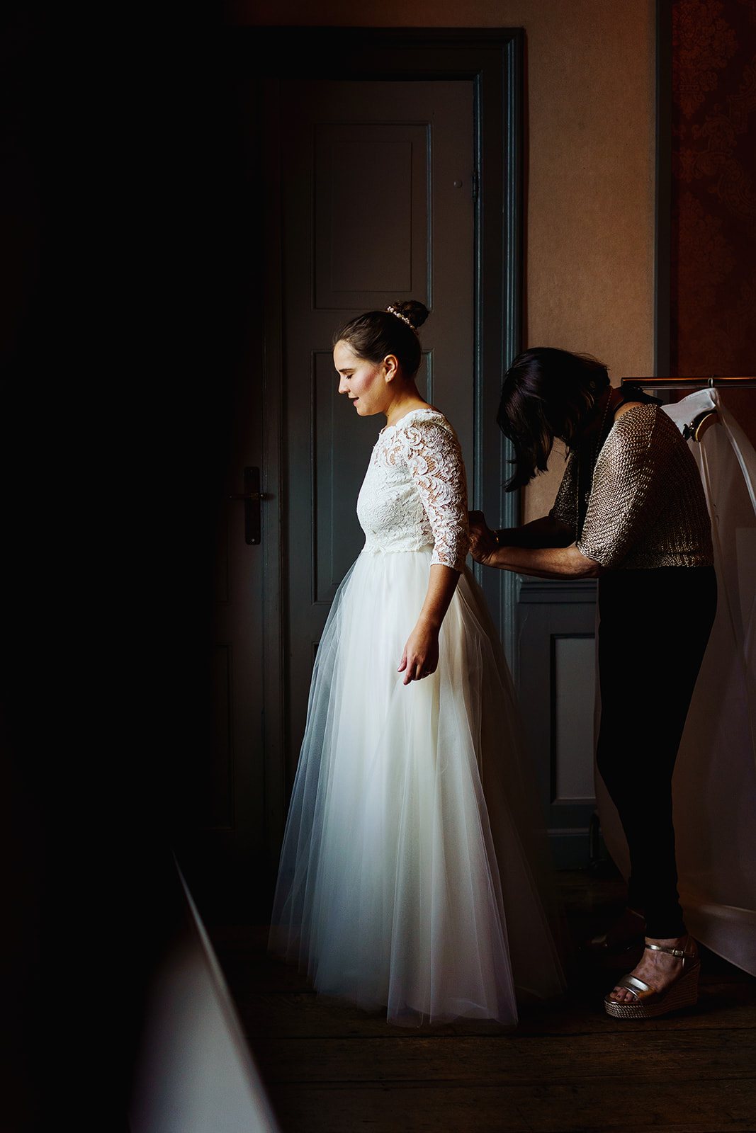De bruidegom trekt haar trouwjurk aan in prachtig licht op Château Neercanne in Maastricht