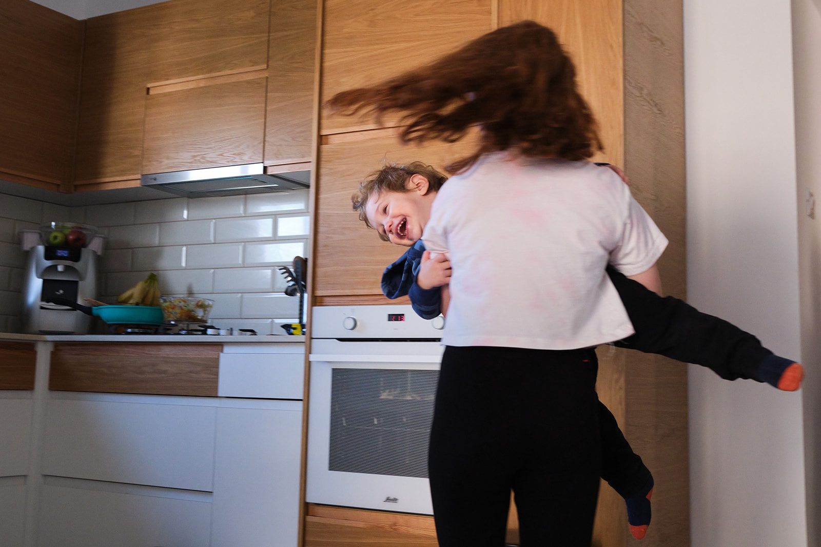 a girl swinging a boy around in the kitchen