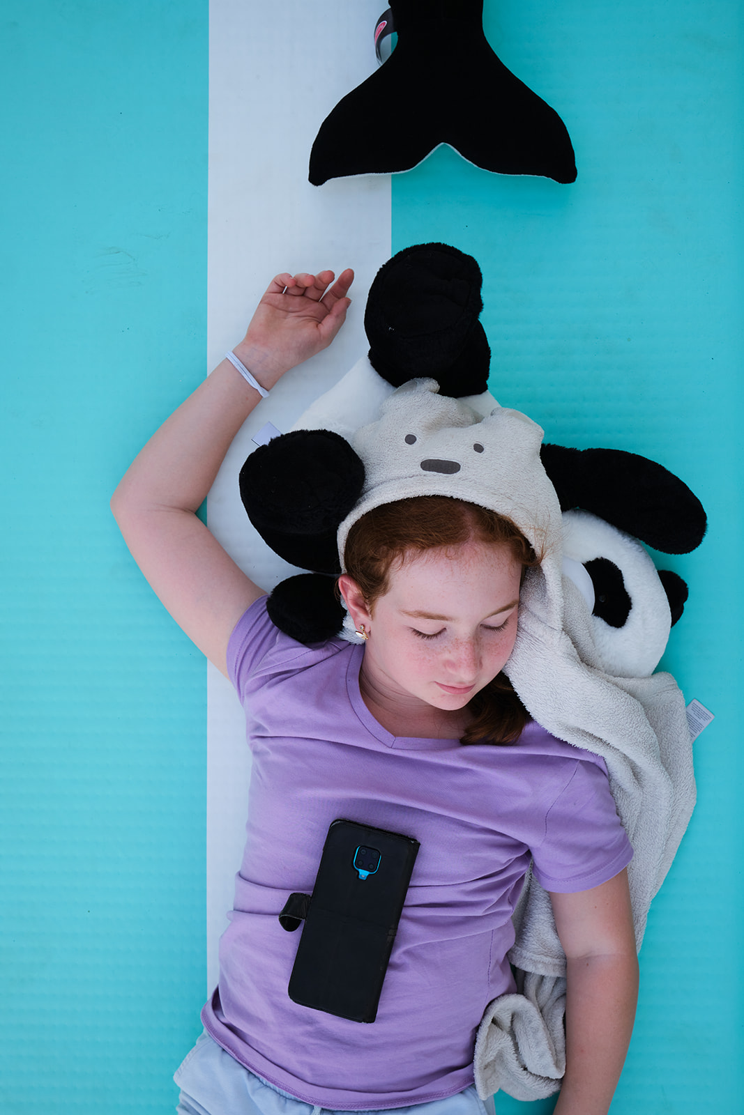 A redhead girl laying on an inflatable mattress with stuffed animals 