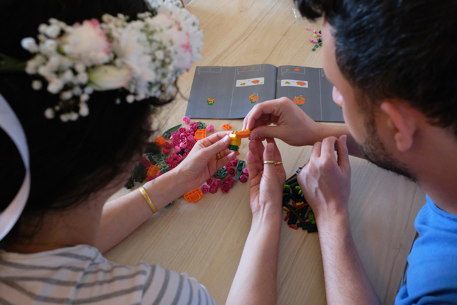 engaged couple building lego flowers together with flowers in her hair