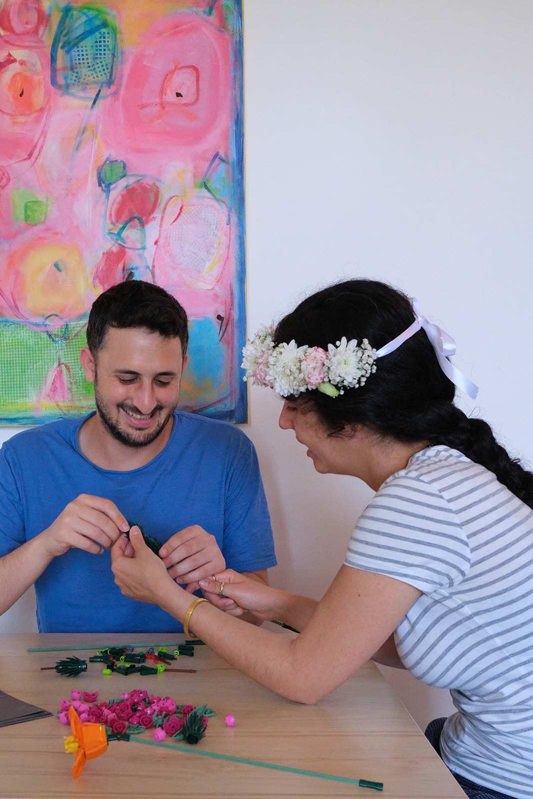 engaged couple building lego flowers together with flowers in her hair