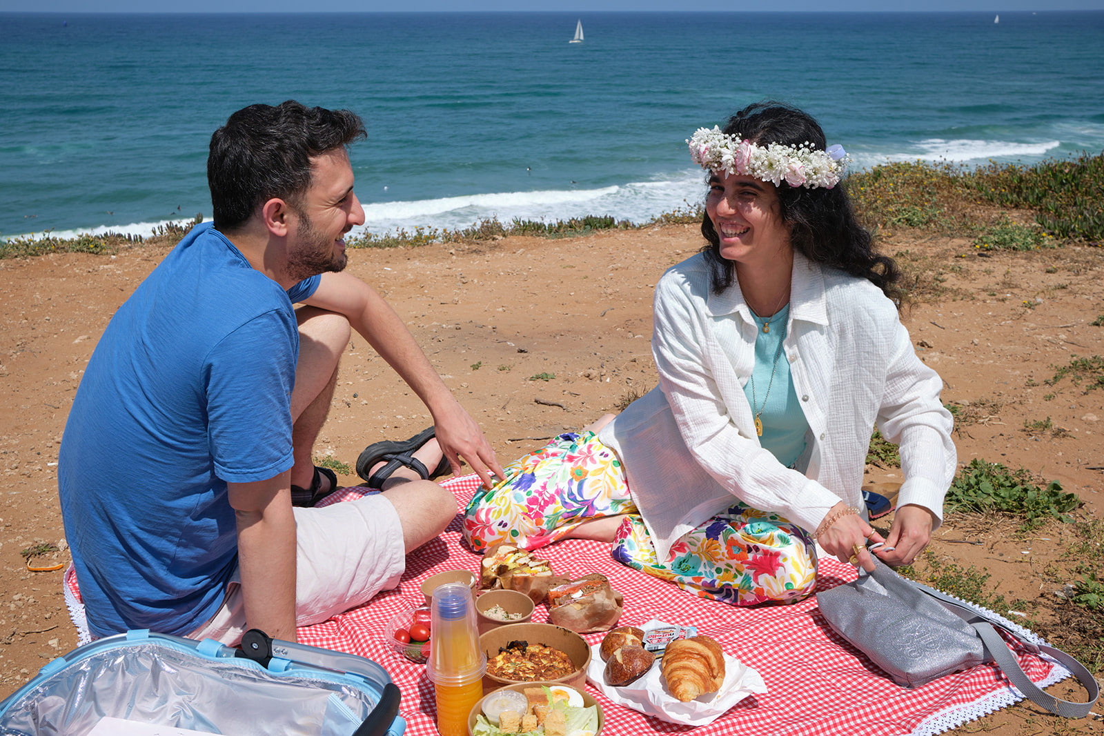 engaged couple having picnic by the beach flowers in her hair