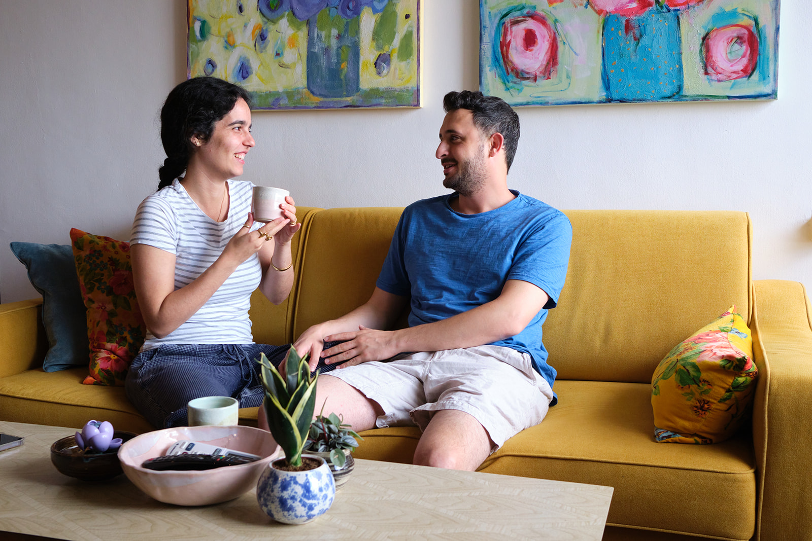 engaged couple looking at each other having coffee in the living room